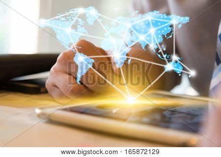 Businessman using computer tablet and finger touching screen with orange light and show blue world map with network conncection line technology conceptual internet globalization concept