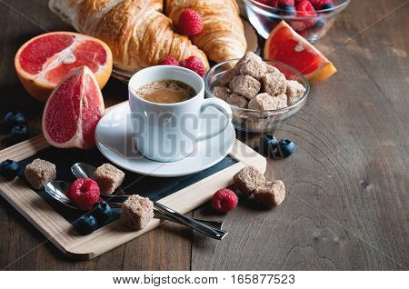 Coffee and croissants with raspberries and fruits for breakfast. Toned image selective focus