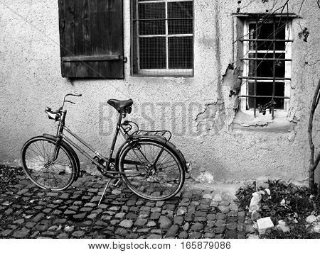 An old fashioned cruising bike on it's kickstand in a small alley outside a rural home