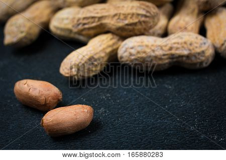 Two Peanuts Without Shells Infront Of Pile Of Peanuts