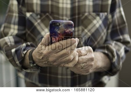 Man in Brown Plaid Shirt Holding iPhone Face On