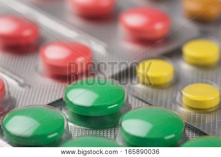 yellow, green and red pills in a silver plastic packaging