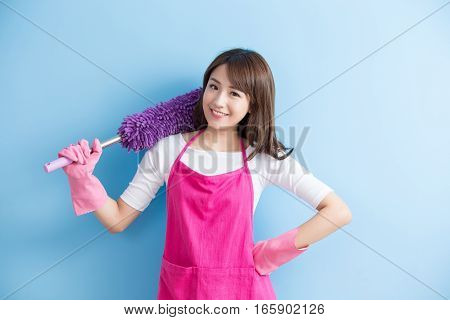 beauty housewife take feather duster and smile to you isolated on blue background asian