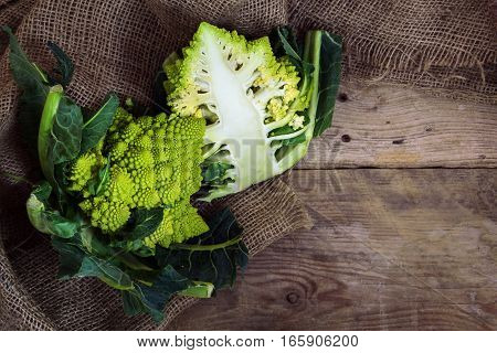 Roman caulifloweror Romanesco broccoli whole and half on a rustic wood top view from above with copy space healthy vegetable Brassica oleracea bred near Rome