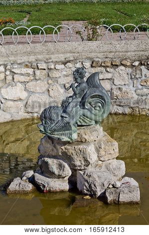 old fountain in Zolochiv castle in Ukraine. Statue of a boy on a dolphin.