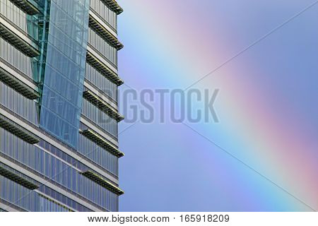 Skyscraper and Rainbow. Detail of a contemporary London skyscraper reflecting the blue sky with a natural rainbow visible in the background.
