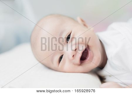 Portrait of cute 3 months Asian baby boy lying down on a blanket and smile.
