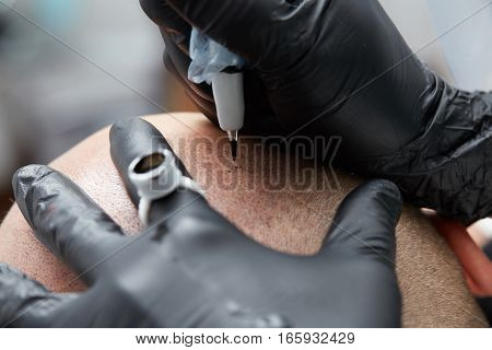 Cosmetologist making permanent makeup on male head - tricopigmentation