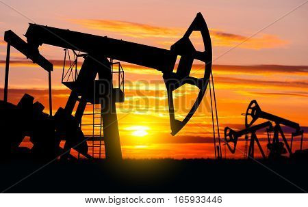 Industrial landscape. Oil Field. Oil pumps against the setting sun.