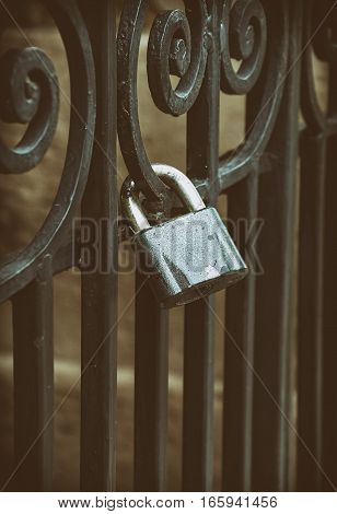 Iron lock on the black forged fence close up vintage toning
