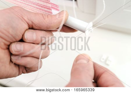 Installing fabric roller blinds. A man pulling the rope that guides the movement of roller blinds.