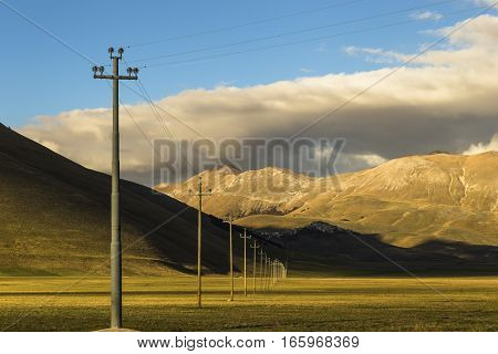 Famous mountain village of Castelluccio di Norcia with beautiful summer landscape at Piano Grande (Great Plain) mountain plateau in the Apennine Mountains on a cloudy day, Umbria, Italy. Low key.