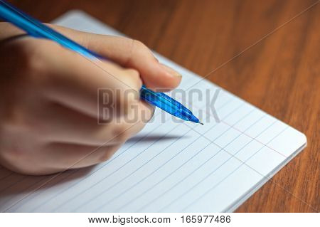 A close photo of a persons writing a letter with a pen.