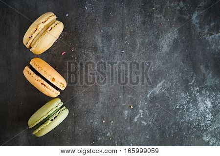 Raw of colorful assorted french macaroons on a dark stone background. Copy space. Top view. Horizontal