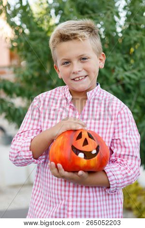 Funny child holding a big pumpkin in the garden