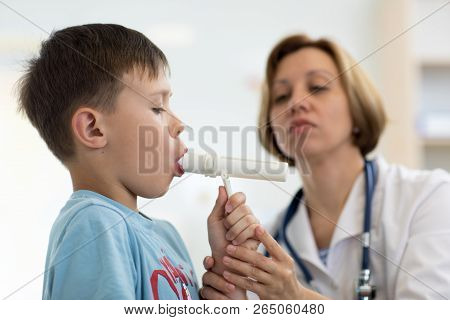 Cute Child Boy Blowing To Peak Metr Medical Device. Doctor Examining Kids Lungs