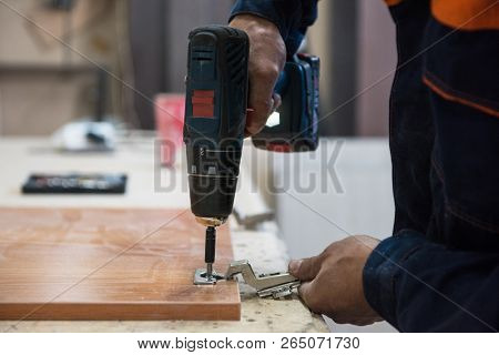 Furniture production concept: man working at machine and making furniture part