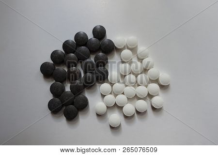 Top View Of Group Of Black Chelated Iron And White Vitamin K Pills