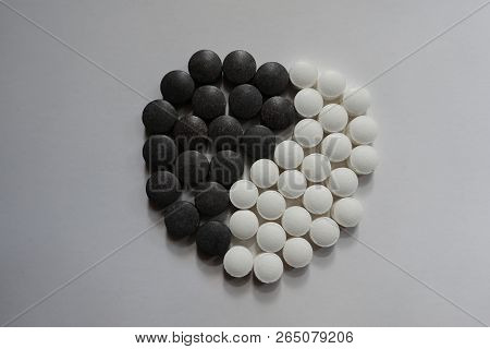 White And Black Pills In Shape Of Yin And Yang Symbol From Above