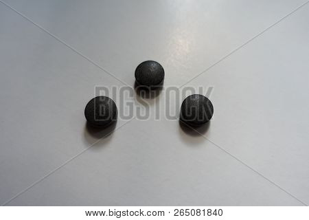 3 Round Black Pills Of Chelated Iron On Neutral Background