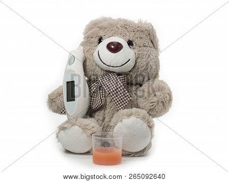 A Generic Toy Bear With An Electronic Themometer And A Cup Of Medicine.