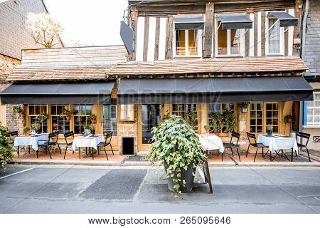 Old Building Facade With Beautiful Restaurant In Honfleur, Famuos French Town In Normandy