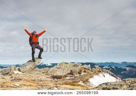 Climber With A Backpack On Top On A Sunny Day. A Man Went Up On The Mountain, People Traveling Throu