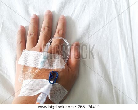 Patient Hand With The Tube Of Normal Saline Infusion On White Cloth Background