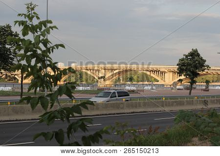 A New Concrete Girder Bridge With Aluminium Rails Spans Over A Large River In The Background. In The