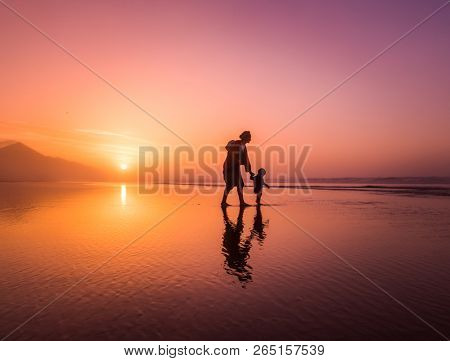 Silhouette of young mother son walking on reflected beach in Cofete, Fuerteventura, Canary Islands, Spain.