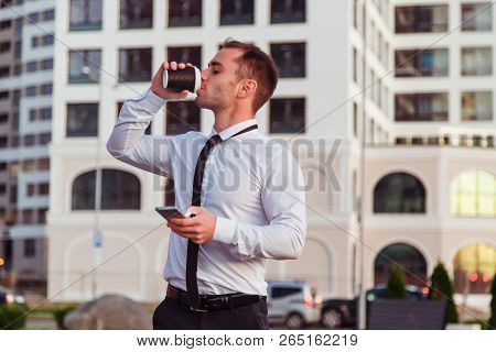 Young Businessman With Smartphone Drinkig A Take Away Coffee