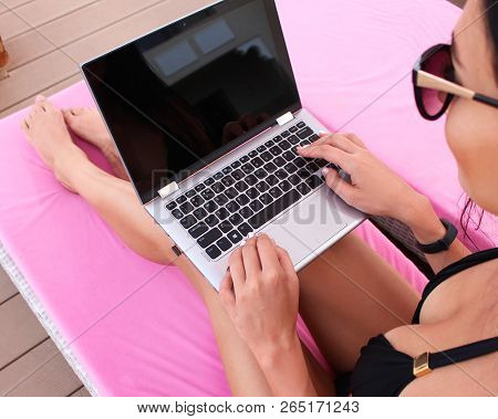 Work And Travel. Incredibly Sexy Girl In A Black Bikini Sits With A Laptop Near The Pool. Find A Tou