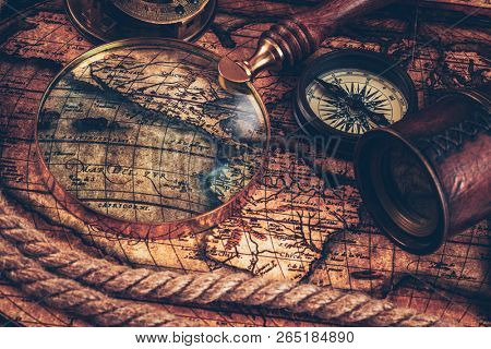 Travel geography navigation concept still life background - old vintage retro compass with sundial, spyglass and rope on ancient world map