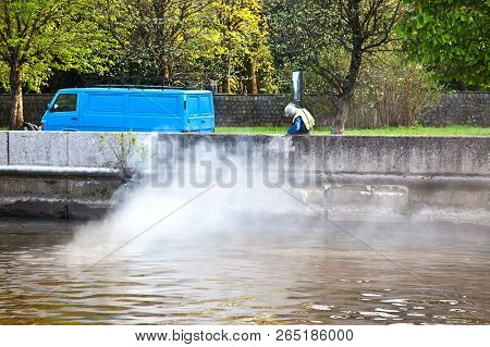 Worker Removes Dirt From The Parapet On The Embankment Of The Pregolya River In The City Of Kalining