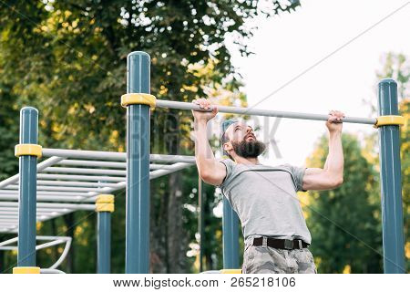 Sport Fitness And Outdoor Training. Man Doing Pull Ups On Bar. Chest Muscles And Biceps Workout.