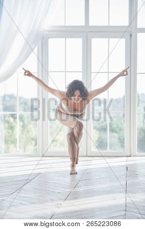 Beautiful Young Woman Practices Yoga Asana Garudasana - Eagle Pose At The Yoga Studio