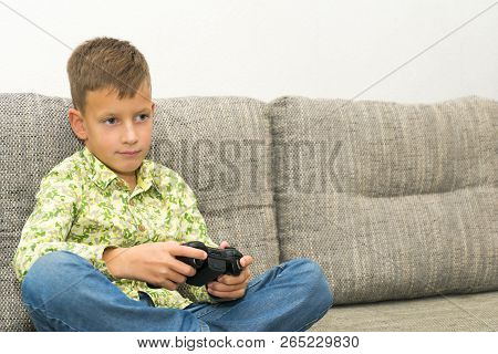 Boy Playing Video Games With Joystic Sitting On Sofa