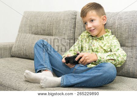 Boy Playing Video Games With Joystic Sitting On Sofa