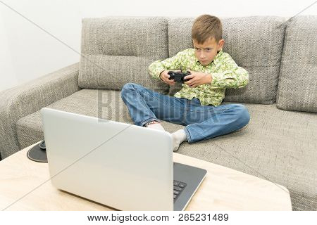 Boy Playing Video Games With Joystic Sitting On Sofa