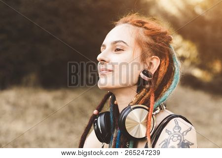 Young Girl With Tattoo And Dreadlocks Listening To Music In The Park