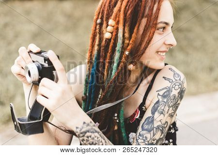 Young Girl With Tattoos And Dreadlocks Photographs Vintage Camera In The Park