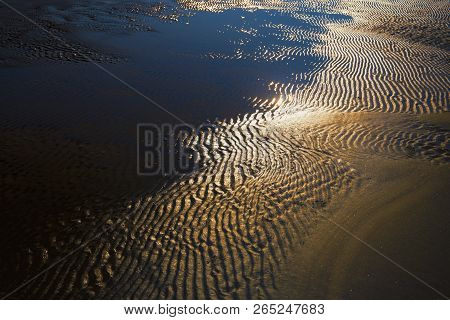 Beach Of Yellow Sand With Waves At Low Tide On A Sunny Day