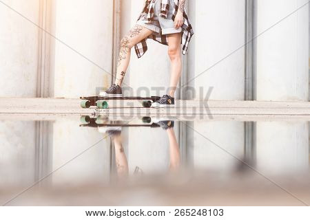 Young Girl With A Longboard On The Background Of Concrete Structure
