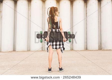 Young Girl With A Longboard On The Background Of Concrete Structure