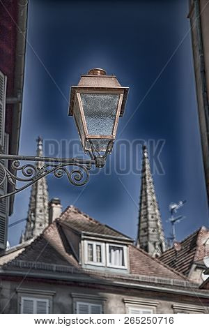 Street Lantern, Roofs, Spiers And Sky. Details Of The Town Obernai, France