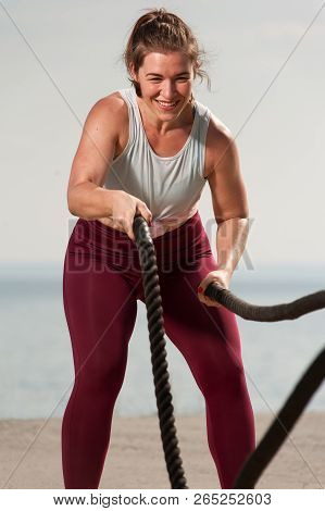 High Intensive Fitness Workout. Work Hard. Young Fit Woman Training With Battle Ropes On The Beach A