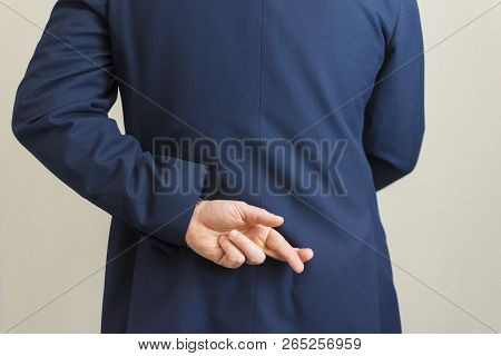 View Of Business Man With His Hands Behind His Back And Fingers Crossed.