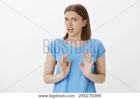 Portrait Of Displeased And Disgusted European Woman In Blue T-shirt, Shaking Palms In Rejection Gest