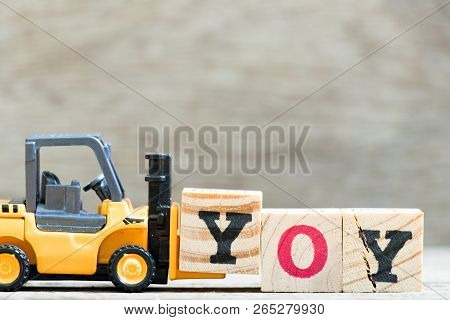Toy Forklift Hold Letter Block  In Word Yoy (abbreviation Of Year Over Year) On Wood Background