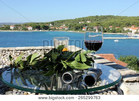 glass of wine and laurel branch with mediterranean village in background, island Zlarin, Croatia
